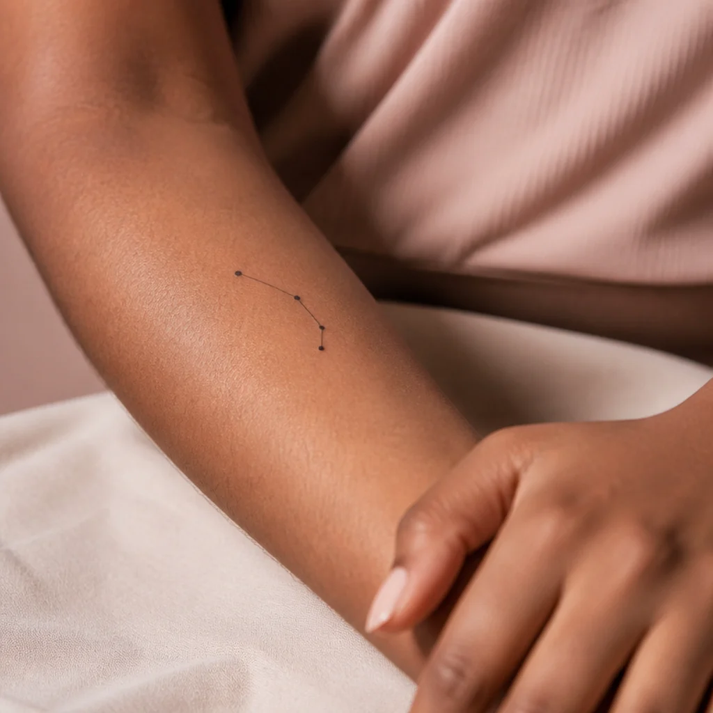 Fine-line Aries constellation tattoo with connected stars on a woman's inner forearm in soft studio light