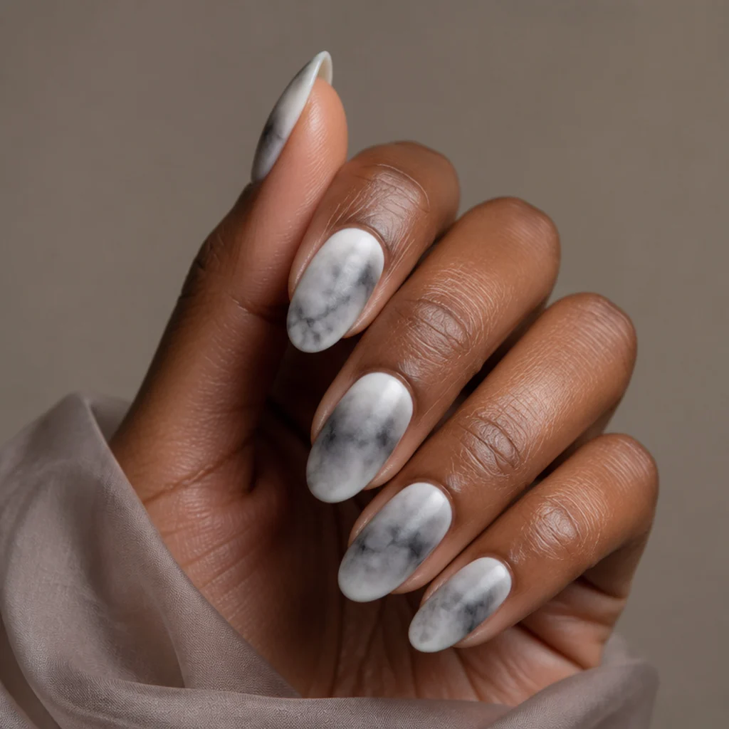 Long oval nails with a soft greyscale blooming gel mist over a white base, charcoal kept low and fading toward the tips, in a minimalist high-fashion editorial macro