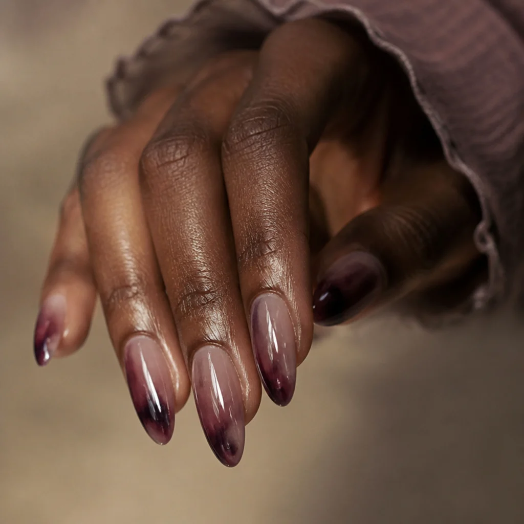 Long almond nails with a smoky plum and mauve blooming gel wash over a translucent base, low saturation with a hint of shimmer, in a moody editorial macro
