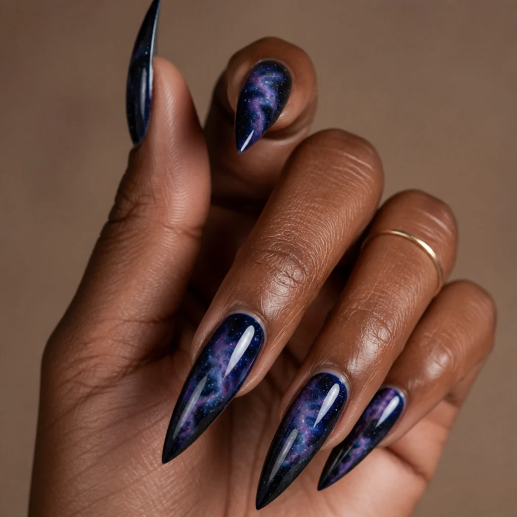 Long stiletto nails with a deep navy and white blooming gel galaxy scattered with tiny star specks, nebulae softened into haze