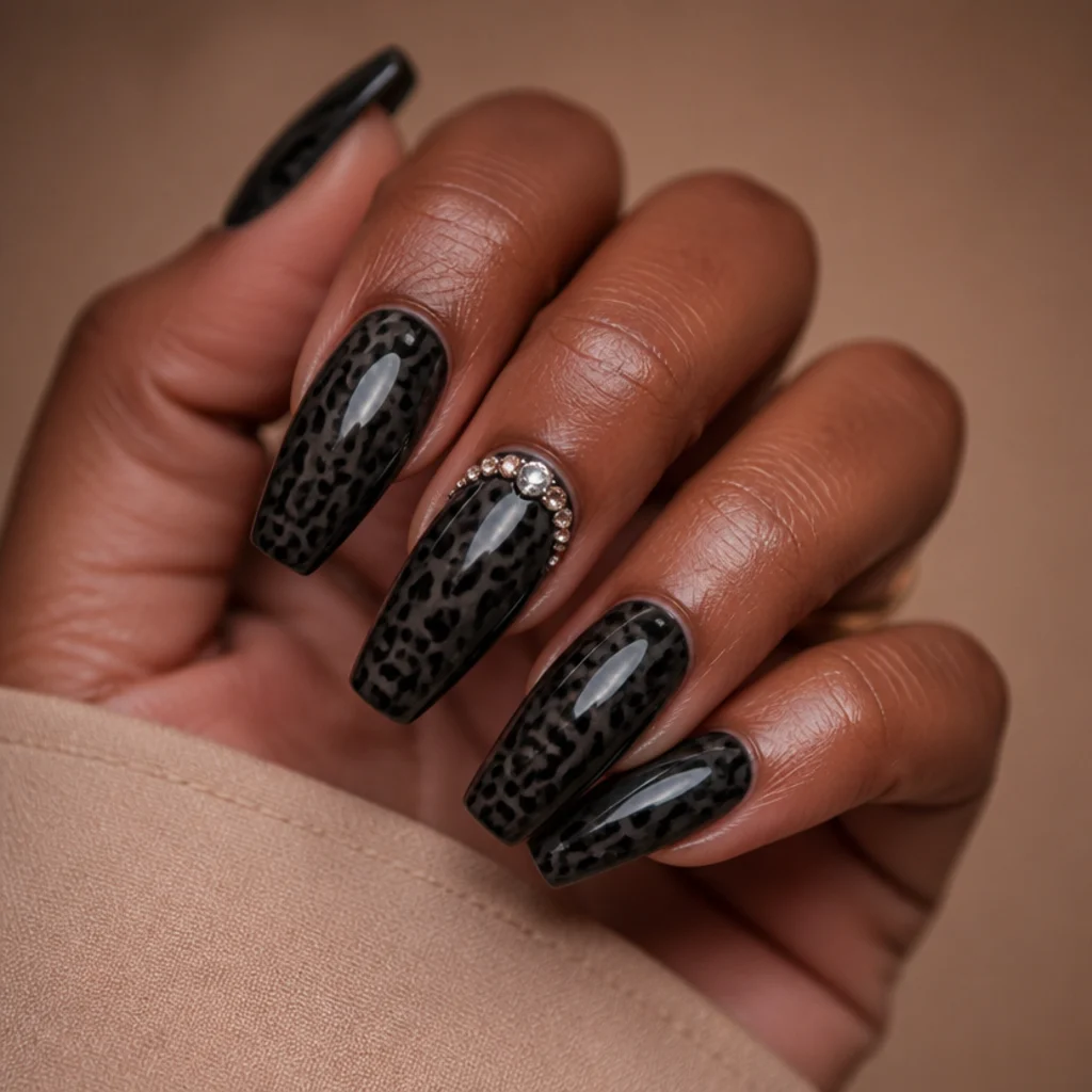 Long coffin nails in black leopard print with a cluster of clear rhinestones near the cuticle