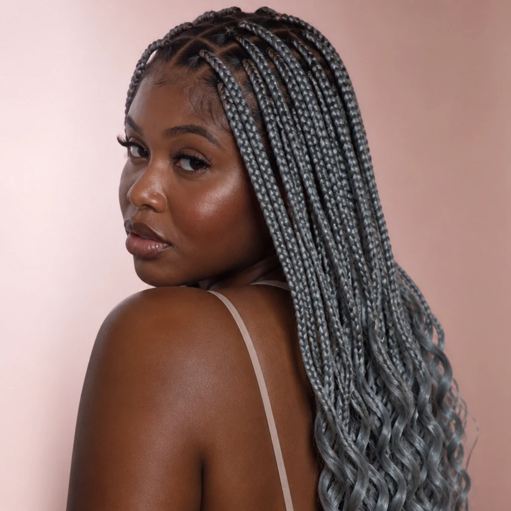 Jumbo box braids in silver-gray with soft curly ends, three-quarter back view, muted blush background on deep-skin model