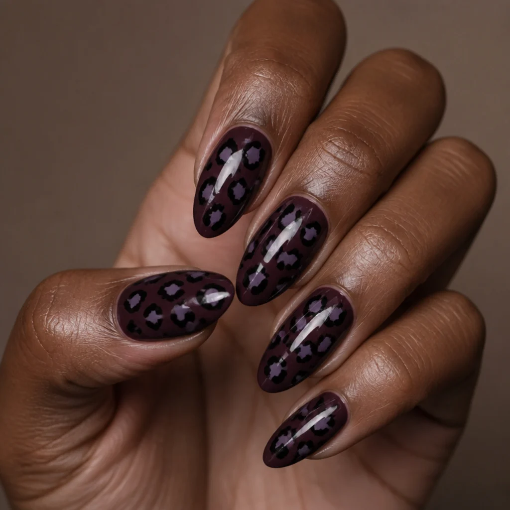 Almond nails with a deep aubergine base and black-and-lavender leopard spots