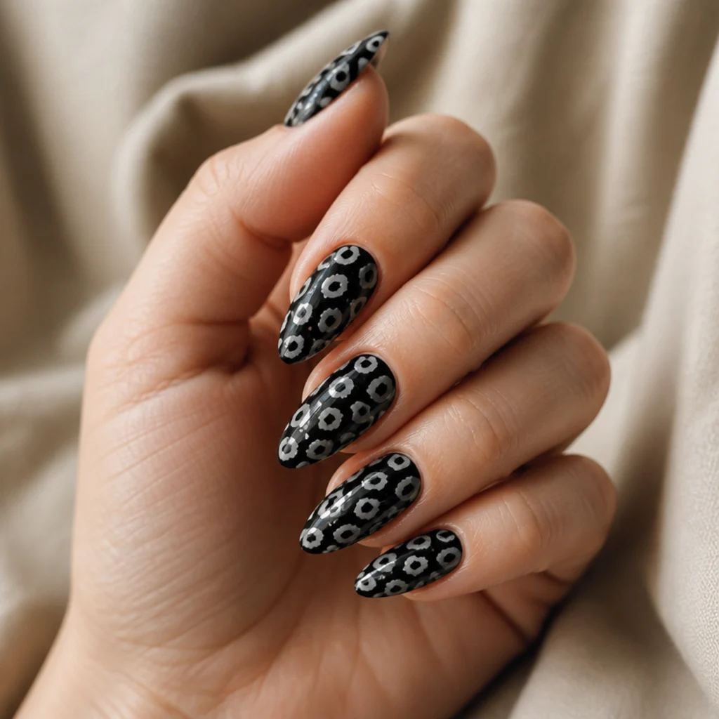 Almond acrylic nails in glossy black with white and soft-gray leopard rosettes painted across the surface